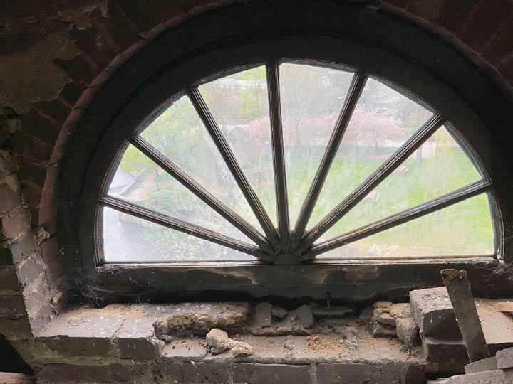 Semi-circular window set in old, crumbling brick.