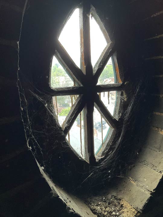 An oval window with wooden radial muntins.