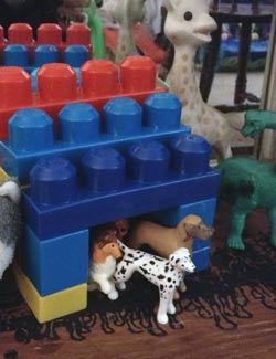 A simple lego dog house with several plastic dogs.
