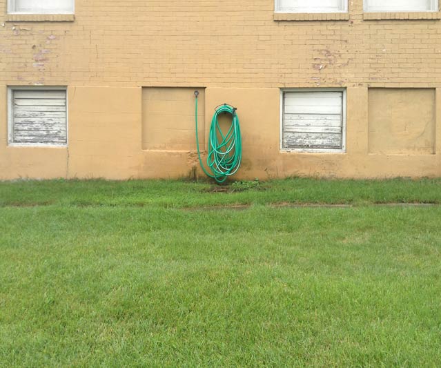 A coiled garden hose on the side of a building.