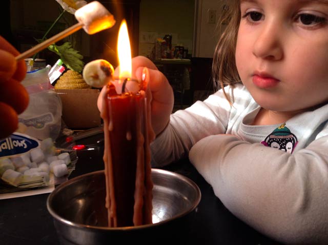 Toasting marshmallows by candle.